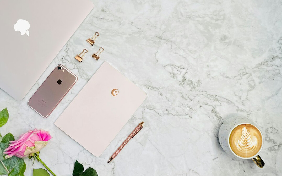 Open notebook and pen on a wooden desk with coffee